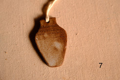 Ceramic ornament vase shape with impressed dashed line bands across the neck and upper body, numbered seven on fabric.