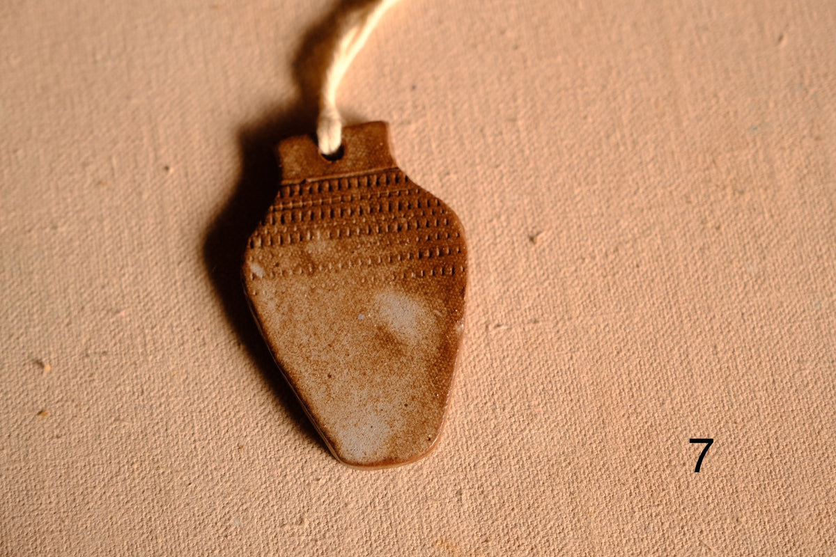 Ceramic ornament vase shape with impressed dashed line bands across the neck and upper body, numbered seven on fabric.