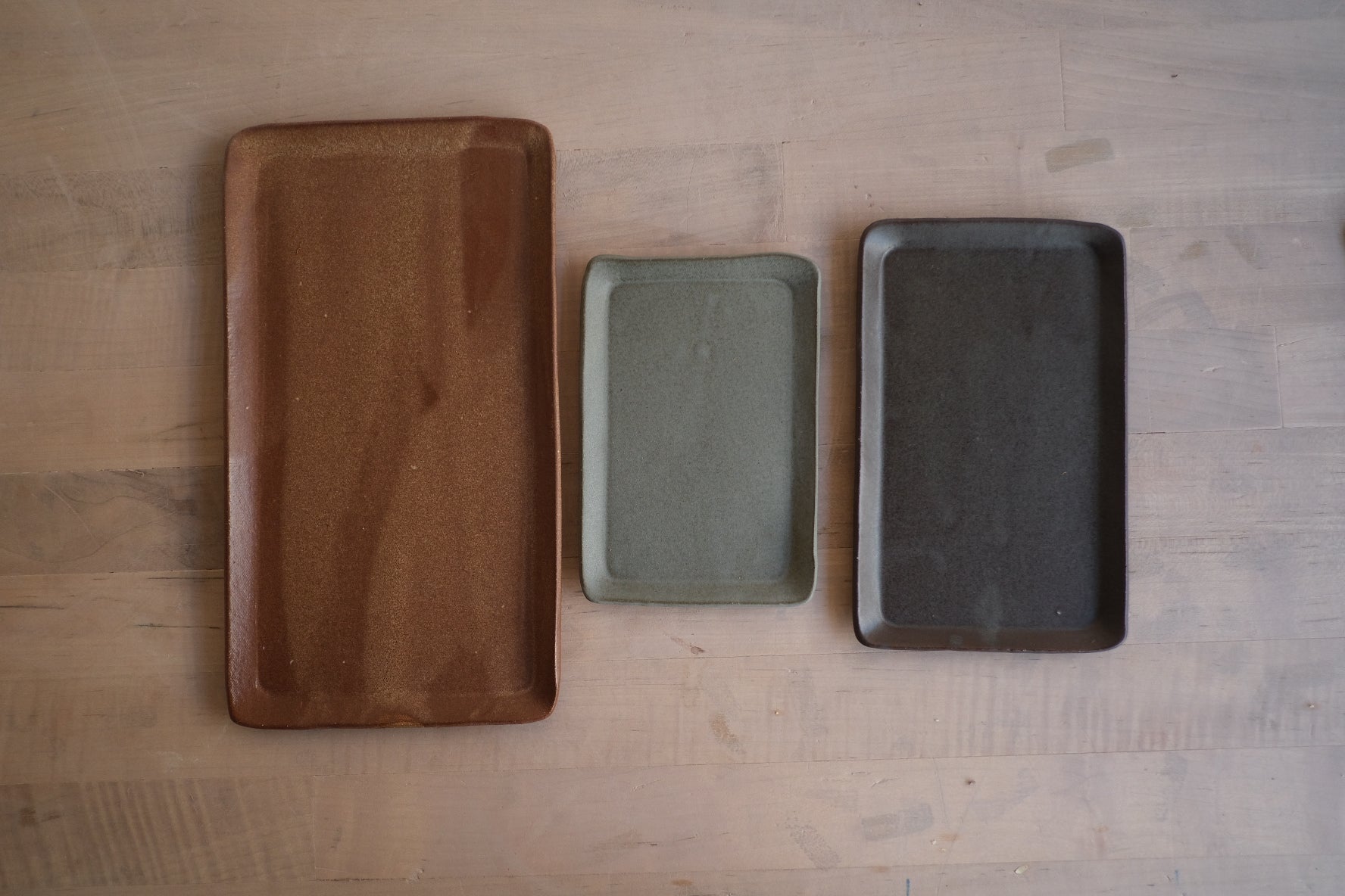 Trinket Tray trio arranged side by side in a row across a light wood table, top-down view showing size differences.