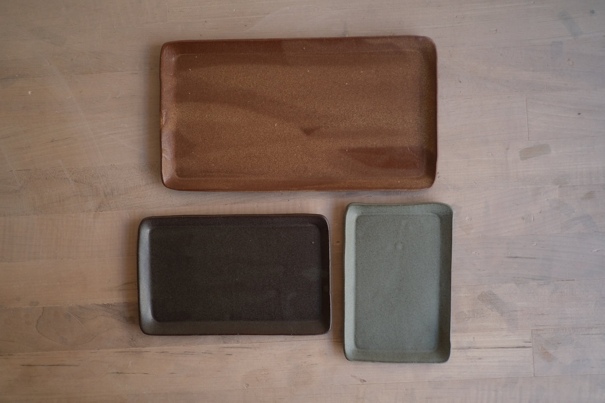 Trinket Tray set of three laid out flat on a wood surface, one large tray above two smaller trays placed side by side.