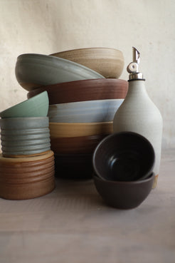 Textured Ramekins stacked beneath a small bowl, set beside a stack of ceramic bowls and an oil bottle with a pour spout.