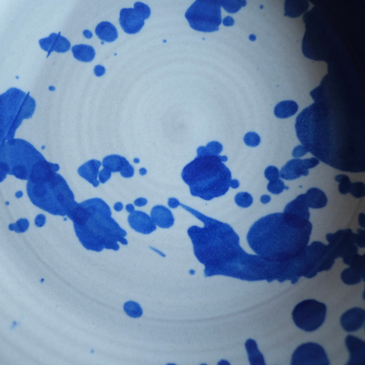 Fat Rim Dinner Plate glaze swatch, close-up of hand-painted cobalt splatter and drips on white glaze.
