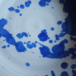 Cobalt blue glaze splatters across an off-white surface with concentric throwing rings by Settle Ceramics.