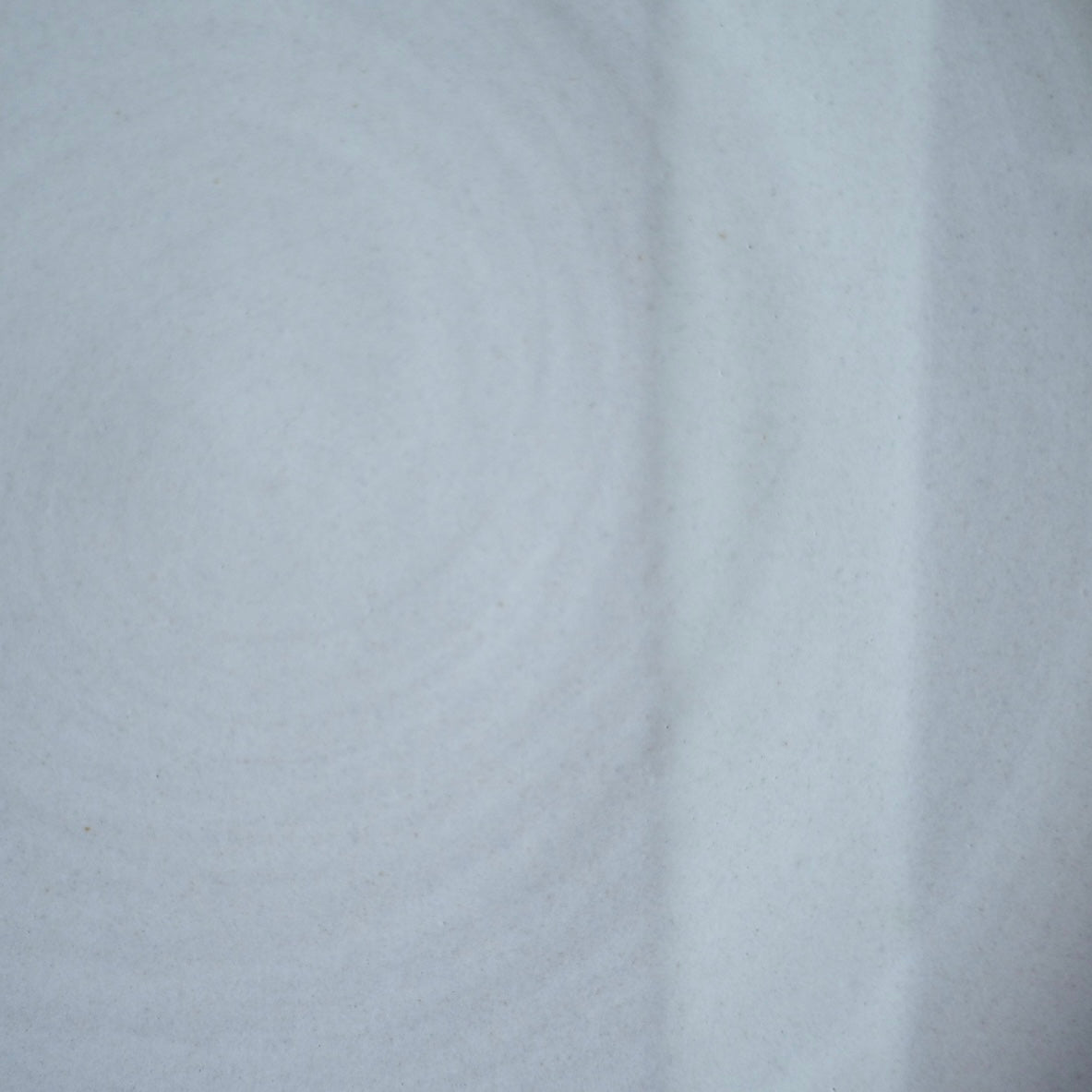 Fat Rim Dinner Plate glaze swatch, macro texture of clean pale grey satin glaze with faint wheel rings.