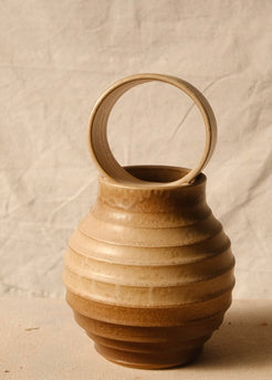 O Orbe Vase shown from a direct front angle under dimmer lighting, highlighting the ribbed body and upright ring handle.