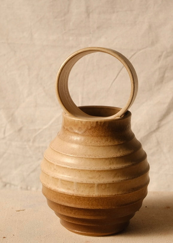 O Orbe Vase shown from a direct front angle under dimmer lighting, highlighting the ribbed body and upright ring handle.