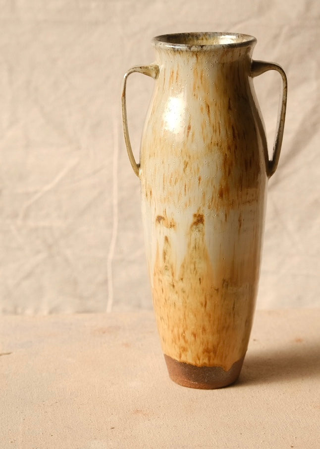 Woodfire Amphora #5 stands upright on cloth, showing both slender loop handles, speckled glaze, and exposed clay base.