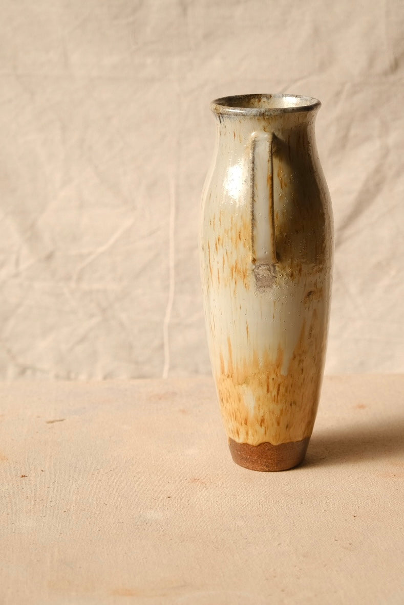 Woodfire Amphora #5 turned in profile, showing the strap handle form, streaked woodfire glaze, and exposed clay foot.