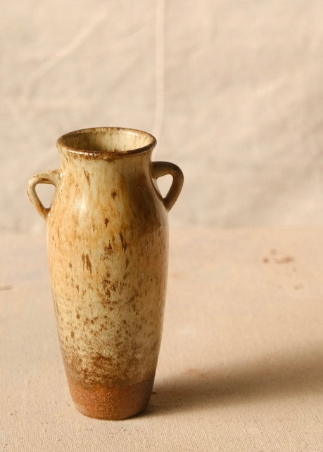 Woodfire Amphora #8 turned to highlight soft wood-ash glaze patterning between twin loop handles on a fabric surface.