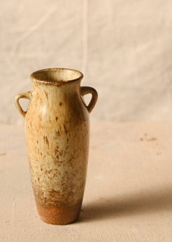 Woodfire Amphora #8 turned to highlight soft wood-ash glaze patterning between twin loop handles on a fabric surface.