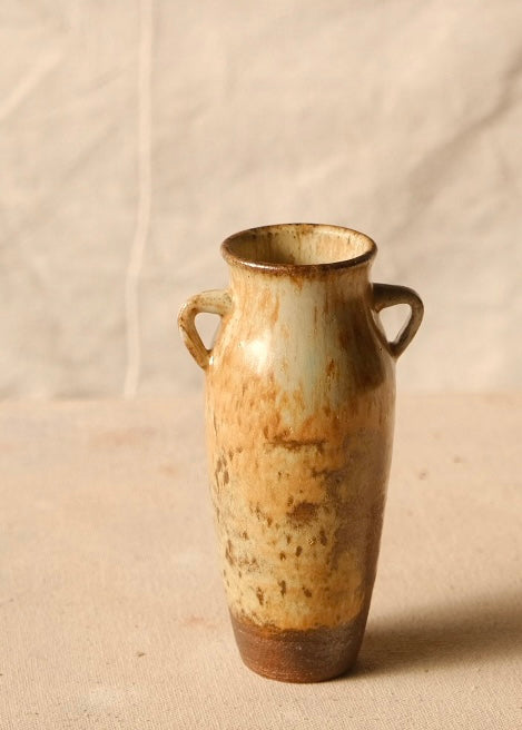 Woodfire Amphora #8 standing upright on cloth, showing its two side handles, flared rim, and unglazed dark base.