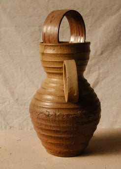Encircled Vase angled with its circular handle facing front, showing horizontal ridges and a ceramic arch in the rim.