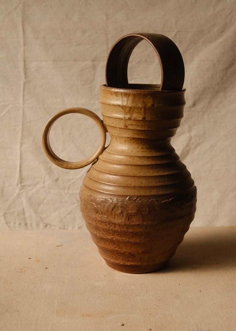 Encircled Vase shown in profile with its round loop handle on the left, horizontal ribs, and ceramic arch in the top.