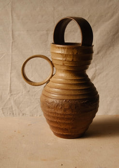 Encircled Vase shown in profile with its round loop handle on the left, horizontal ribs, and ceramic arch in the top.