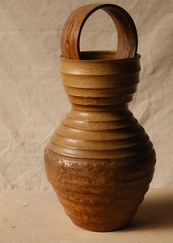 Encircled Vase seen from the handle-free back, highlighting its ribbed ceramic walls and an arch resting in the mouth.