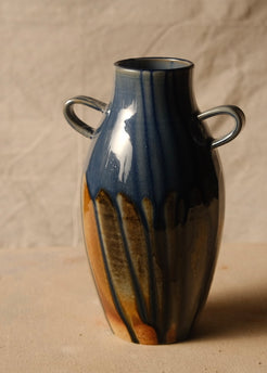 Woodfire Amphora #9, ceramic vase with two loop handles and dripped glaze, front view on a canvas-covered surface.