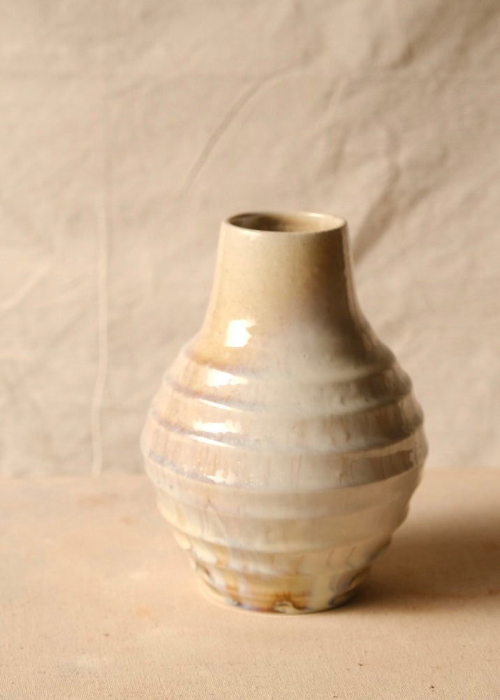 Woodfire Ripple Vase, single ceramic vase with ribbed bulbous body, narrow neck, and glossy glaze on canvas surface.
