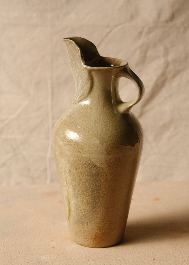 Woodfire Carafe on canvas, angled view showing the loop handle on the right and tall pulled spout facing left.
