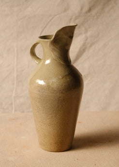 Woodfire Carafe angled right, with curved handle on the left, raised rim, and glossy glaze pooling over matte clay.