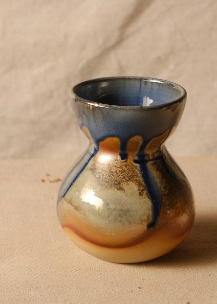 Woodfire Sake Carafe #1 on canvas fabric, showing its flared rim and glazed bulbous body with dark drips.