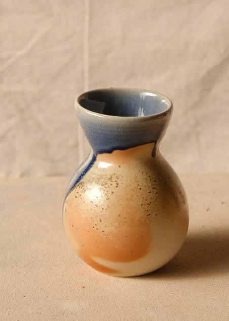 Woodfire Sake Carafe #2 turned to show speckled flashings, warm clay body, and heavily glazed blue neck and shoulder.