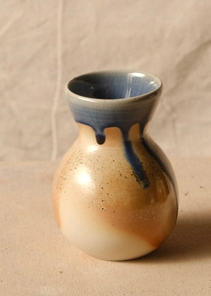 Woodfire Sake Carafe #2 viewed from an angle showing short blue glaze drips stopping near the shoulder of the round body.