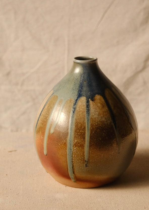 Woodfire Orbe Vase turned slightly right, revealing blue-gray glaze running over a speckled warm surface.