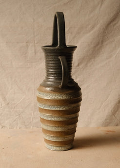Eros Amphora shown in profile from the side, highlighting one curved handle and the tall overhead loop against fabric.