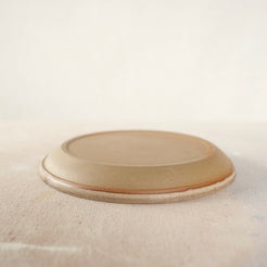 Country Rim Lunch Plate resting inverted on cloth, showing the unglazed flat stoneware underside and smooth rim.