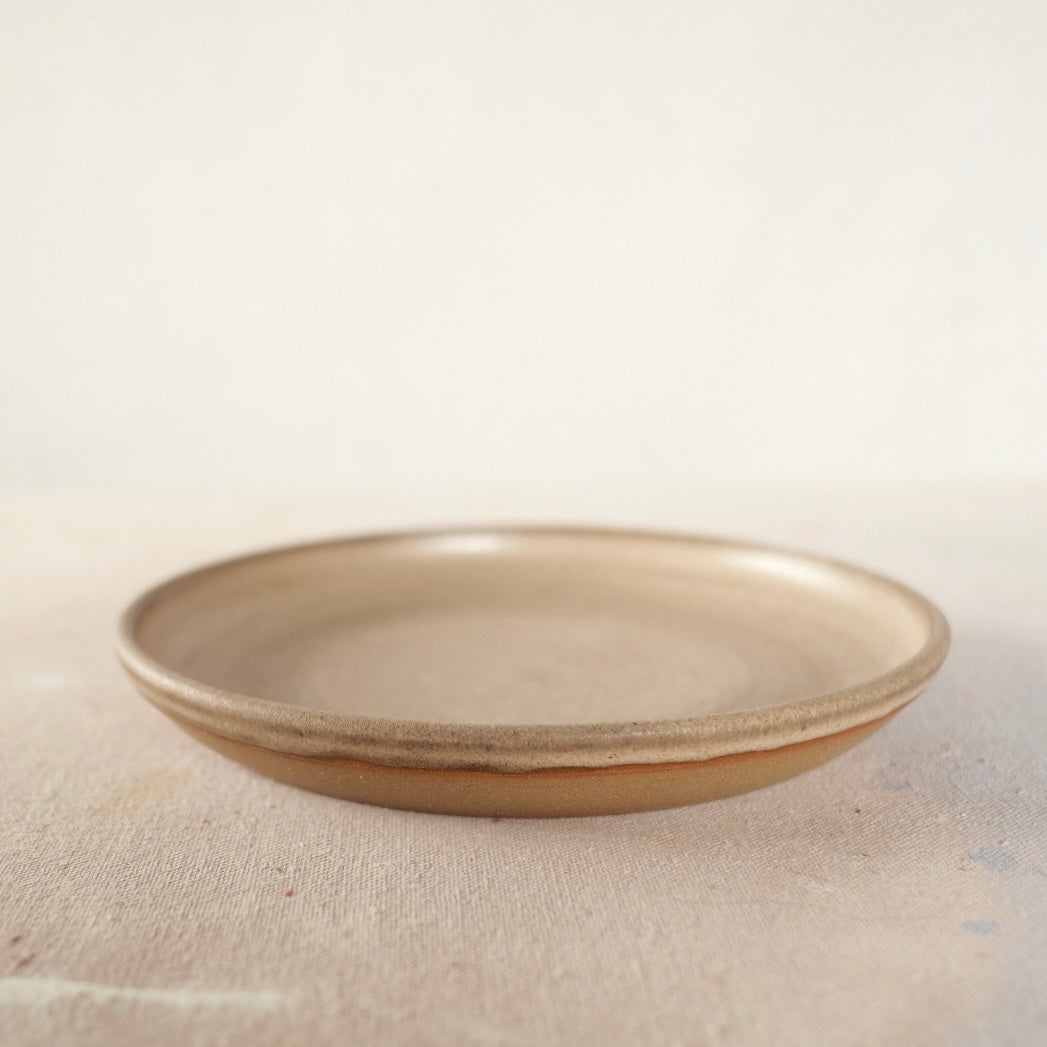 Country Rim Lunch Plate sits upright at a low angle, showing its glazed shallow interior and exposed clay base.