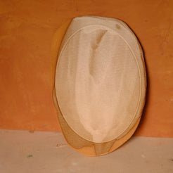 Wide Tera Platter in satin beige glaze propped upright, showing an oval well, wavy raw rim, and exposed clay patch.