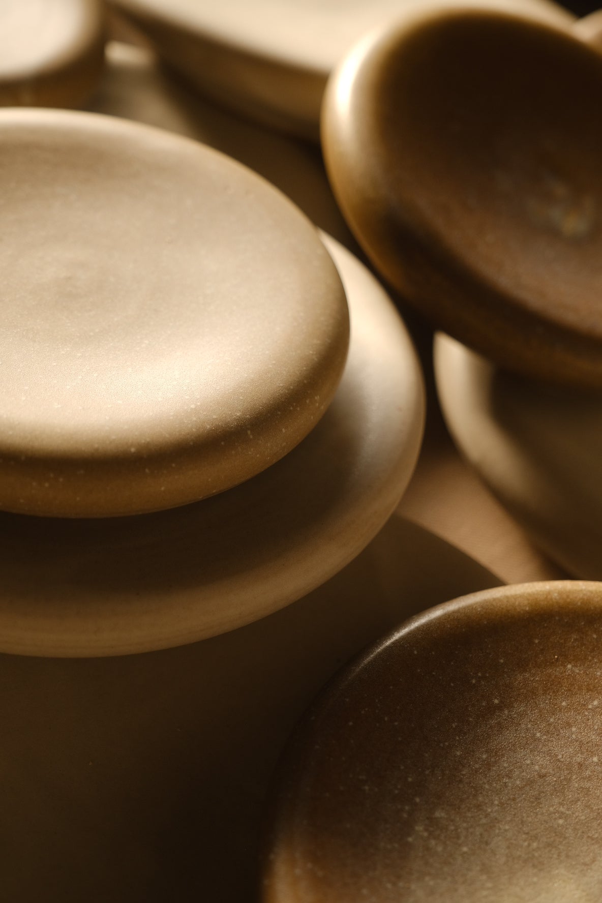 Bubble Plates stacked and clustered at close range, showing smooth stoneware surfaces and thick, rounded puffy rims.