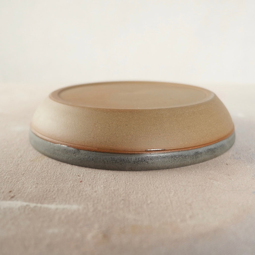 Country Rim Dinner Bowl turned upside down on canvas, showing the wide unglazed stoneware foot.