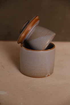 Butterbell ceramic crock with smooth pale purple-grey glaze and subtle dipped edge, lid resting inverted on the crock rim.