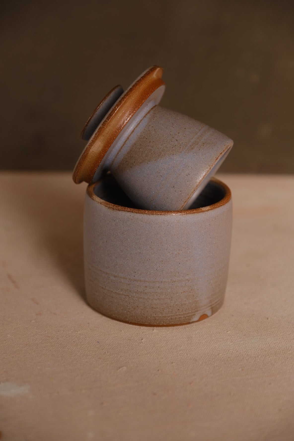 Butterbell ceramic crock with smooth pale purple-grey glaze and subtle dipped edge, lid resting inverted on the crock rim.