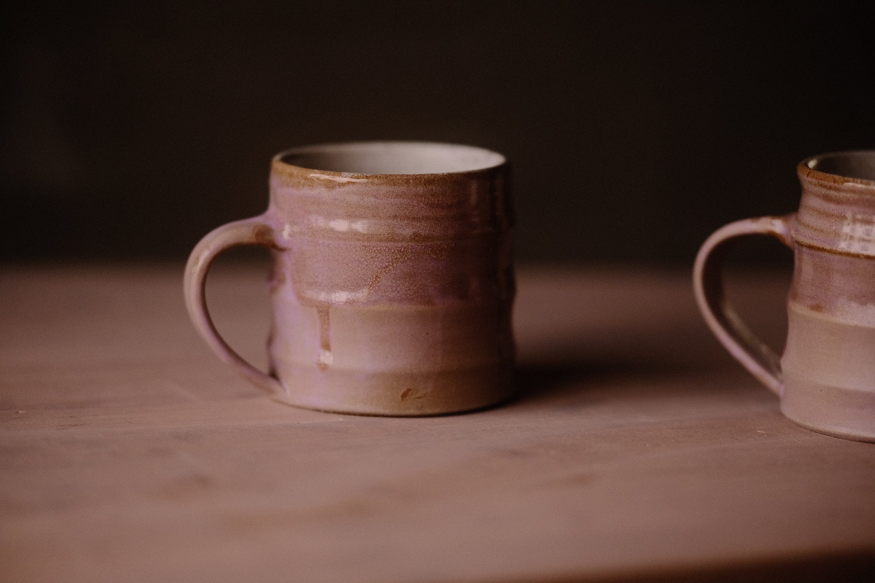Lavender Salt Big Mug on a flat surface, with glaze drips and an arched handle beside the rim of a second mug.