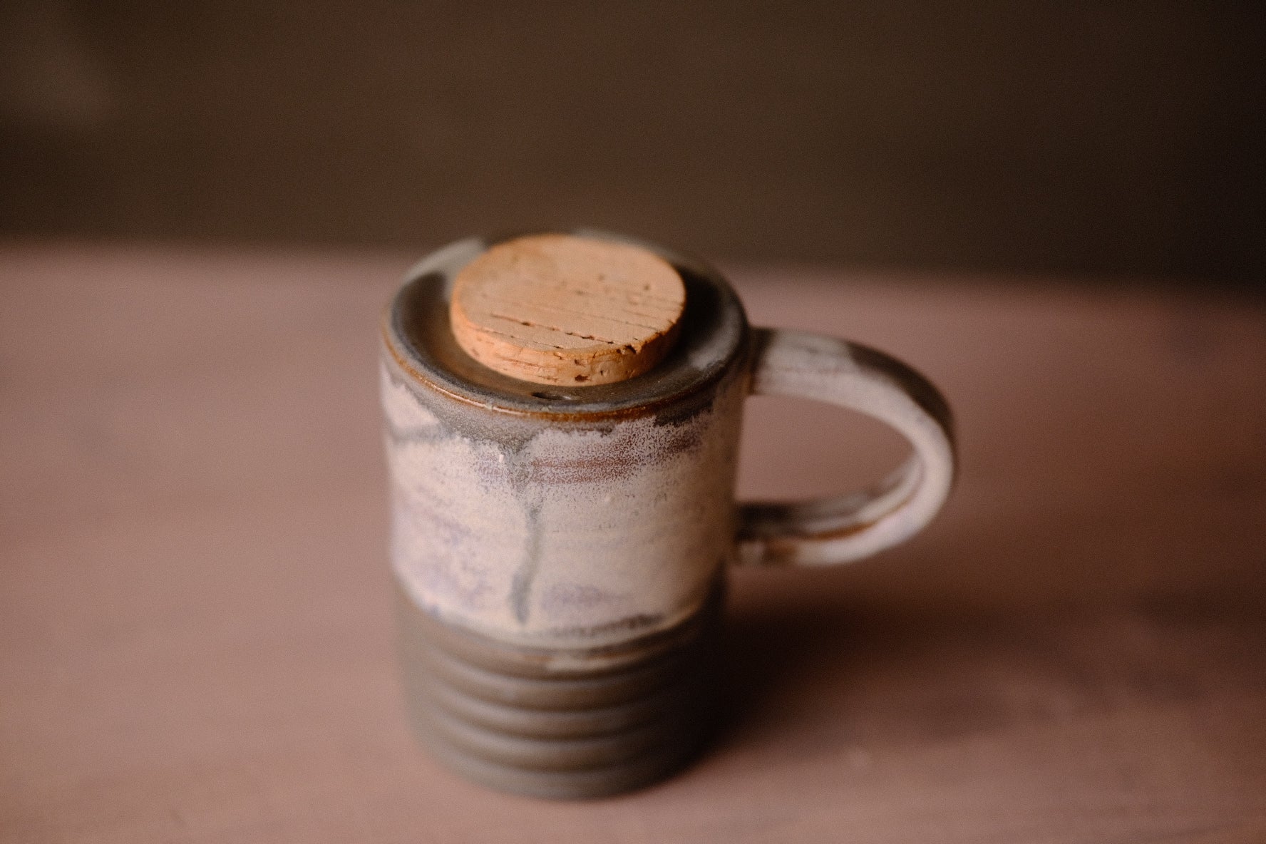 Stormy Sky Traveller mug, close-up of the round cork stopper set in the rim, dark grey glazed neck, handle on right.