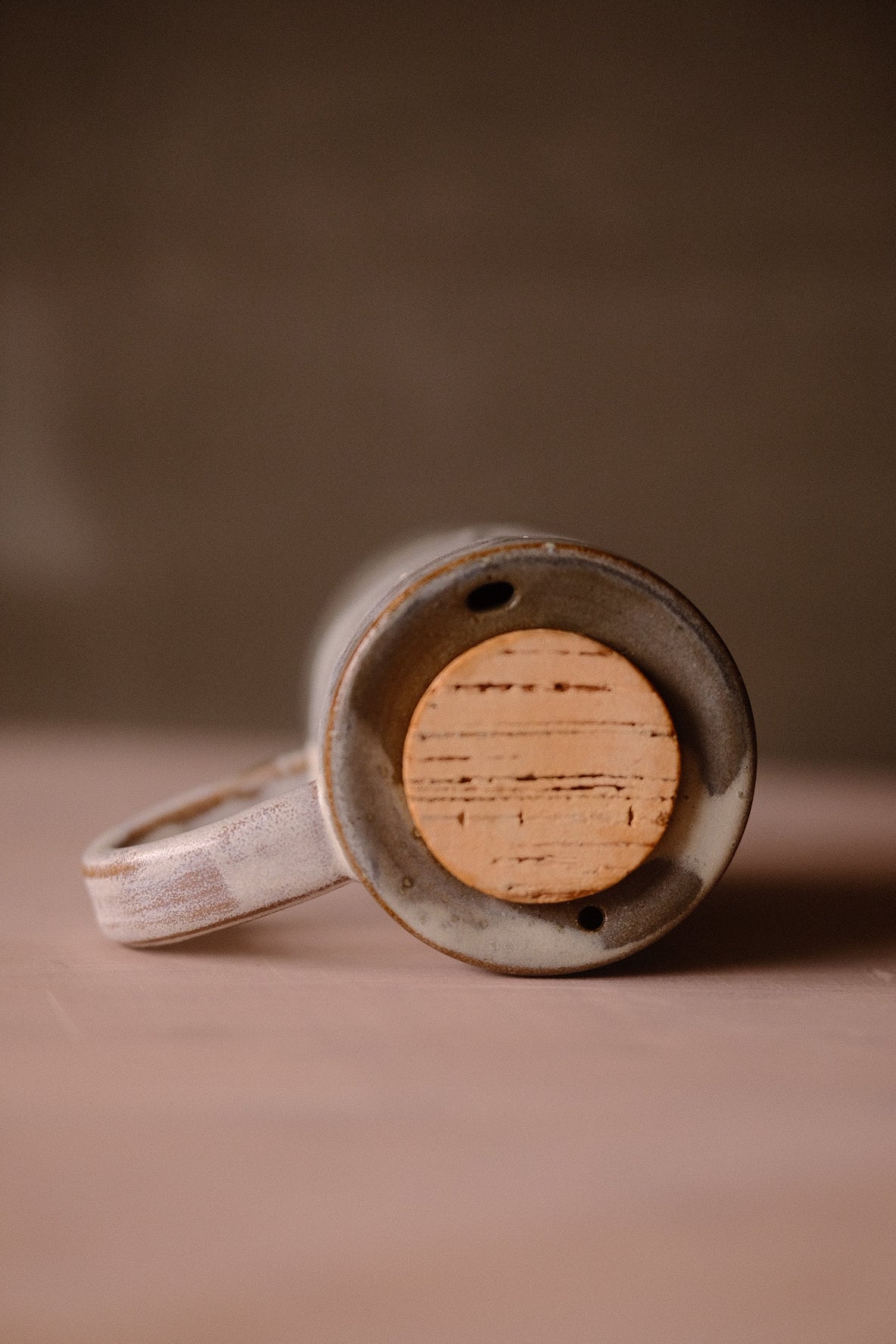 Stormy Sky Traveller mug resting tilted on its side, showing the flat cork lid and two small holes in the grey glazed rim.