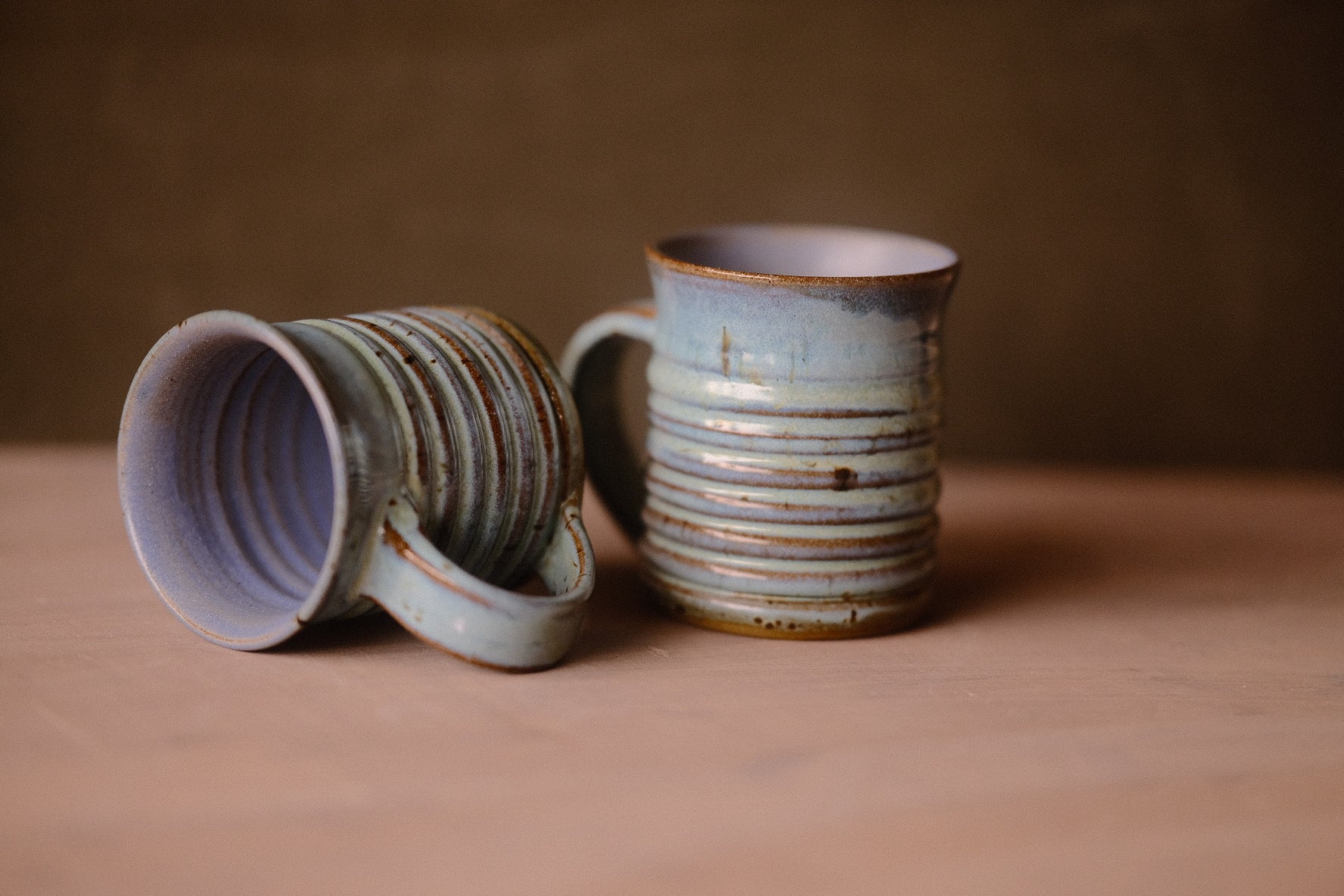 Two Secret Cenote Little Mugs on wood, one standing upright and one tilted on its side revealing the interior.
