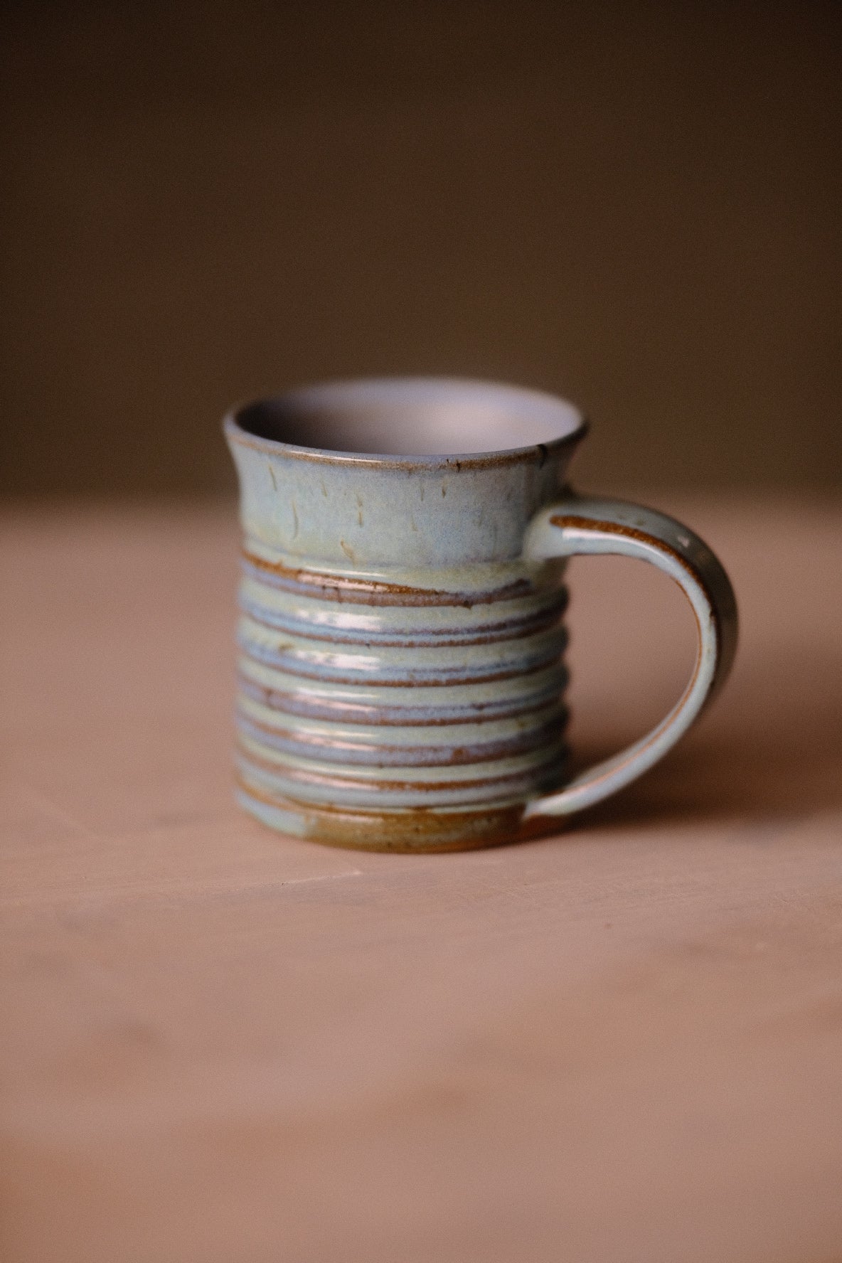 Secret Cenote Little Mug standing on a wooden surface with ribbed ridges and handle to the right.