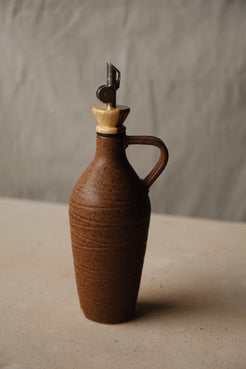 Tejas Oil Bottle in reddish brown stoneware with a handle, wood collar and metal pour spout.