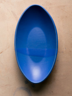 Wander Oval Server, top-down view of solid matte blue glazed stoneware dish on studio surface.