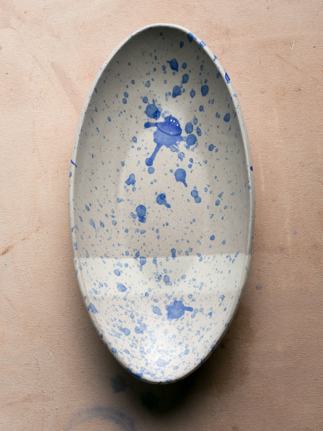 Wander Oval Server, top-down view of white dish with fine and bold blue splatter glaze.
