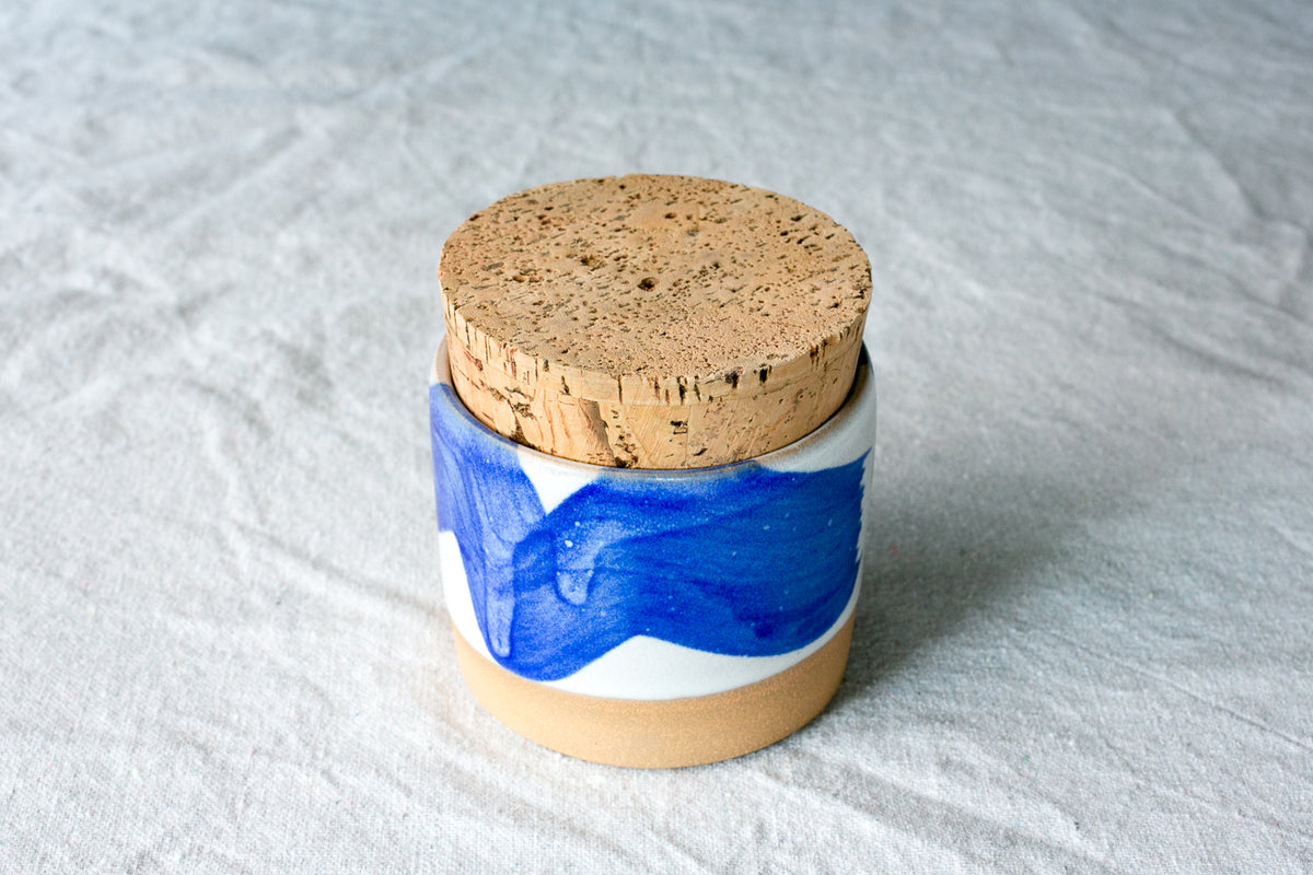 Wander Salt Jar featuring a bold blue brushstroke glaze pattern over white ceramic with cork stopper.