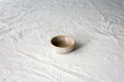 Wander Tiny Bowl in speckled brown glaze with a dusted white rim and exterior band, set on textured cloth.