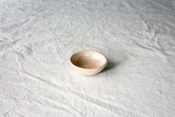 Wander Tiny Bowl in smooth glossy cream glaze, centered at a high three-quarter angle on textured cloth.