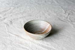 Wander Side Bowl in speckled neutral stoneware showing thrown interior rings on woven linen fabric.