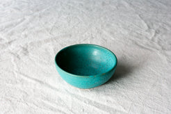 Wander Side Bowl single round dish in teal glaze with subtle speckles resting on textured linen fabric.