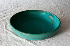 Wander Dinner Bowl with speckled teal interior glaze, angled view showing wide rim and shallow basin on cloth