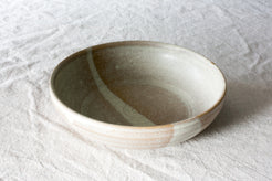 Wander Pasta Bowl in two-tone glaze with spiral interior, resting on crinkled linen fabric.